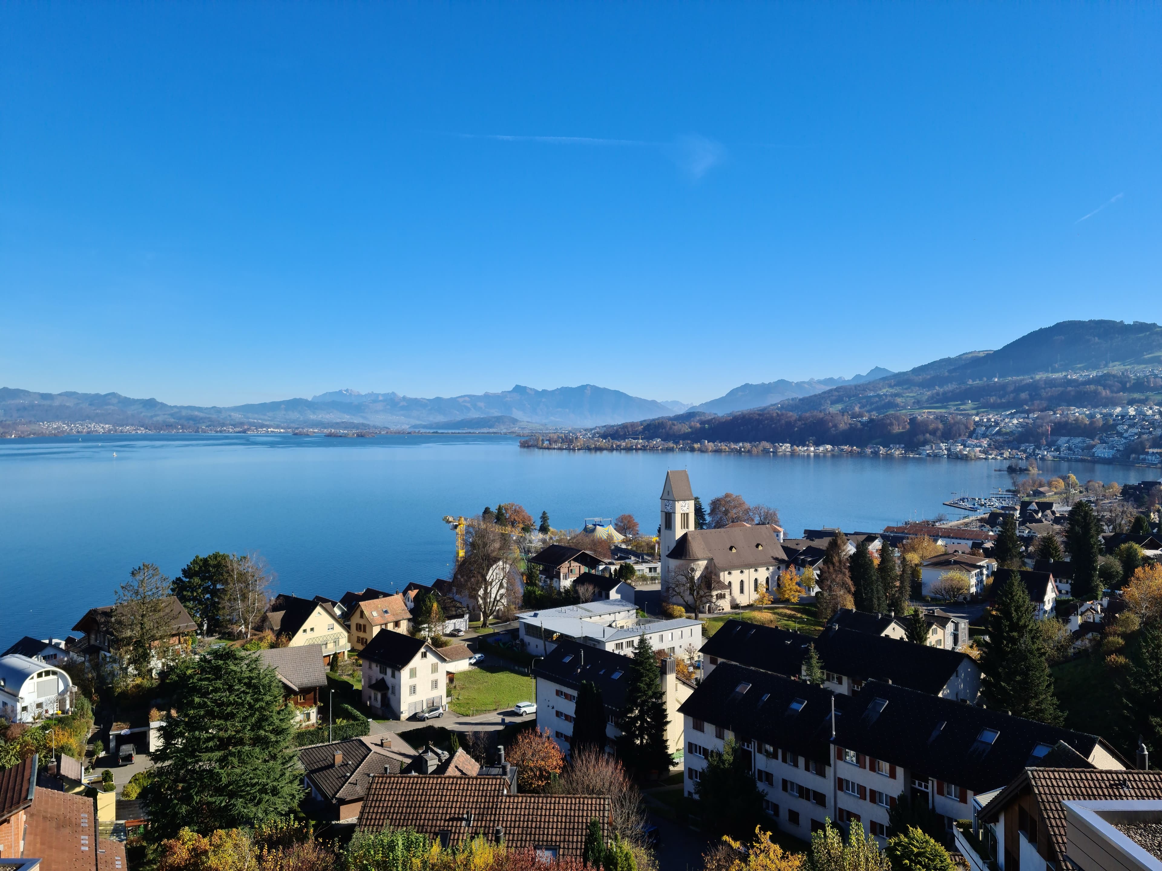 Homes and a church above Lake Zurich at Richterswil, with the Alps across the water